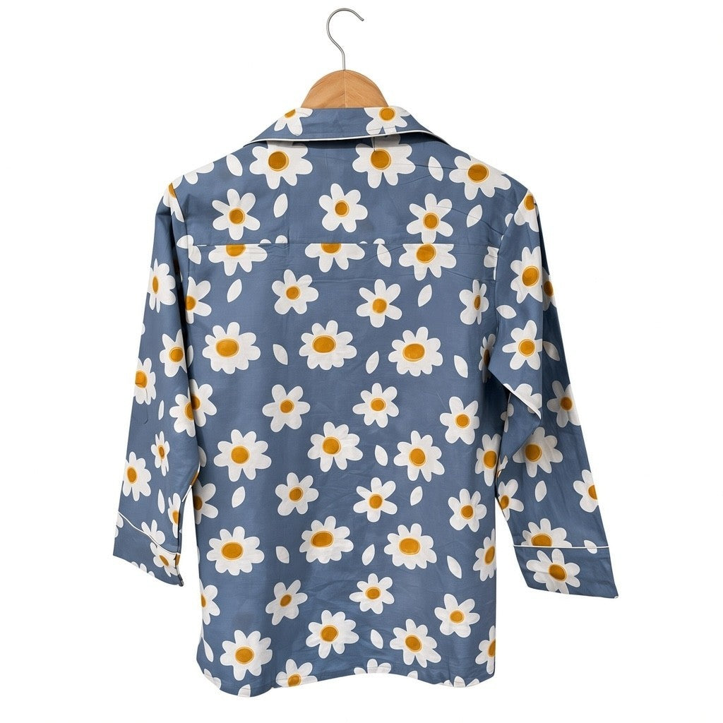 Wild Lotus UK blue cotton pyjama top with white daisy print, revere collar, and white piping detail on a hanger.
